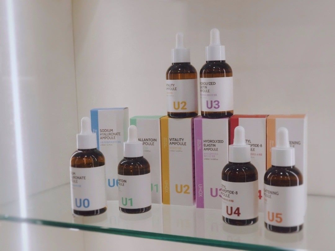 玻璃層架上的韓國安瓶產品，編號 U0 到 U5 的棕色滴管瓶與外盒
