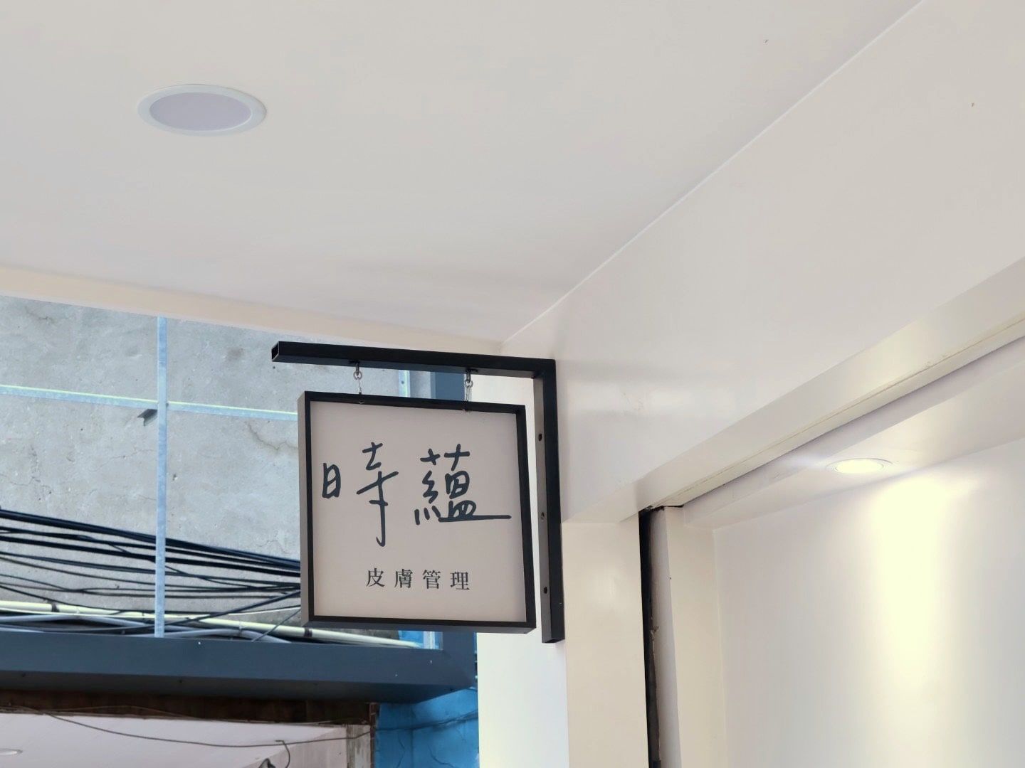 時蘊工作室門口的黑色鐵框掛招牌,寫著「時蘊 皮膚管理」